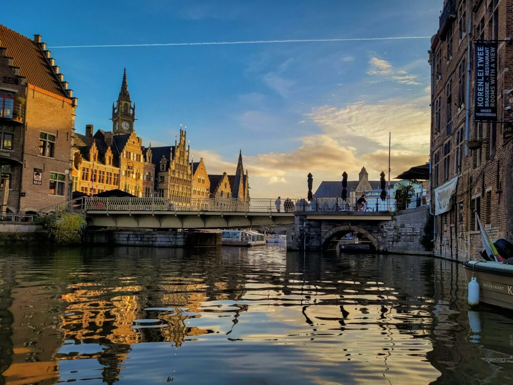 The river Leie in the historic centre of Ghent at dusk, with a bridge and the towers of the old town