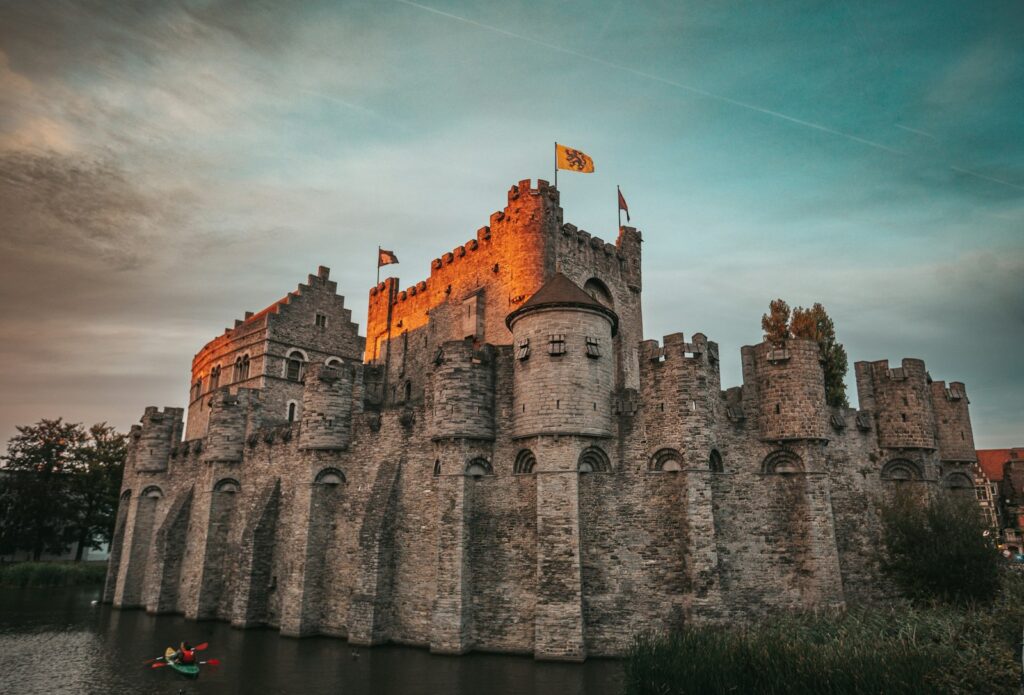 Gravensteen castle in Ghent at dusk, with the moat in the foreground